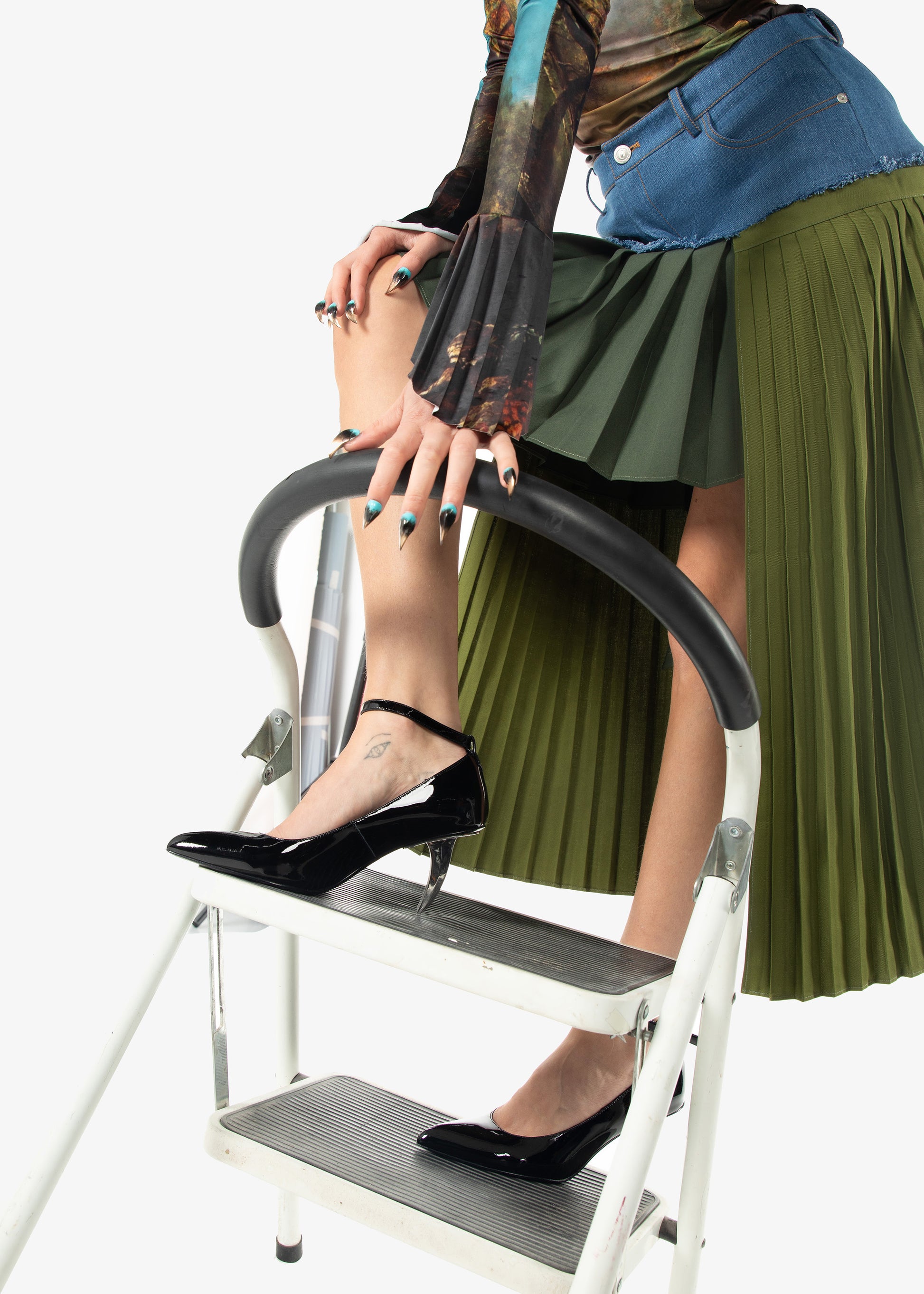 Person wearing Riverpeace green pleated skirt and black shoes