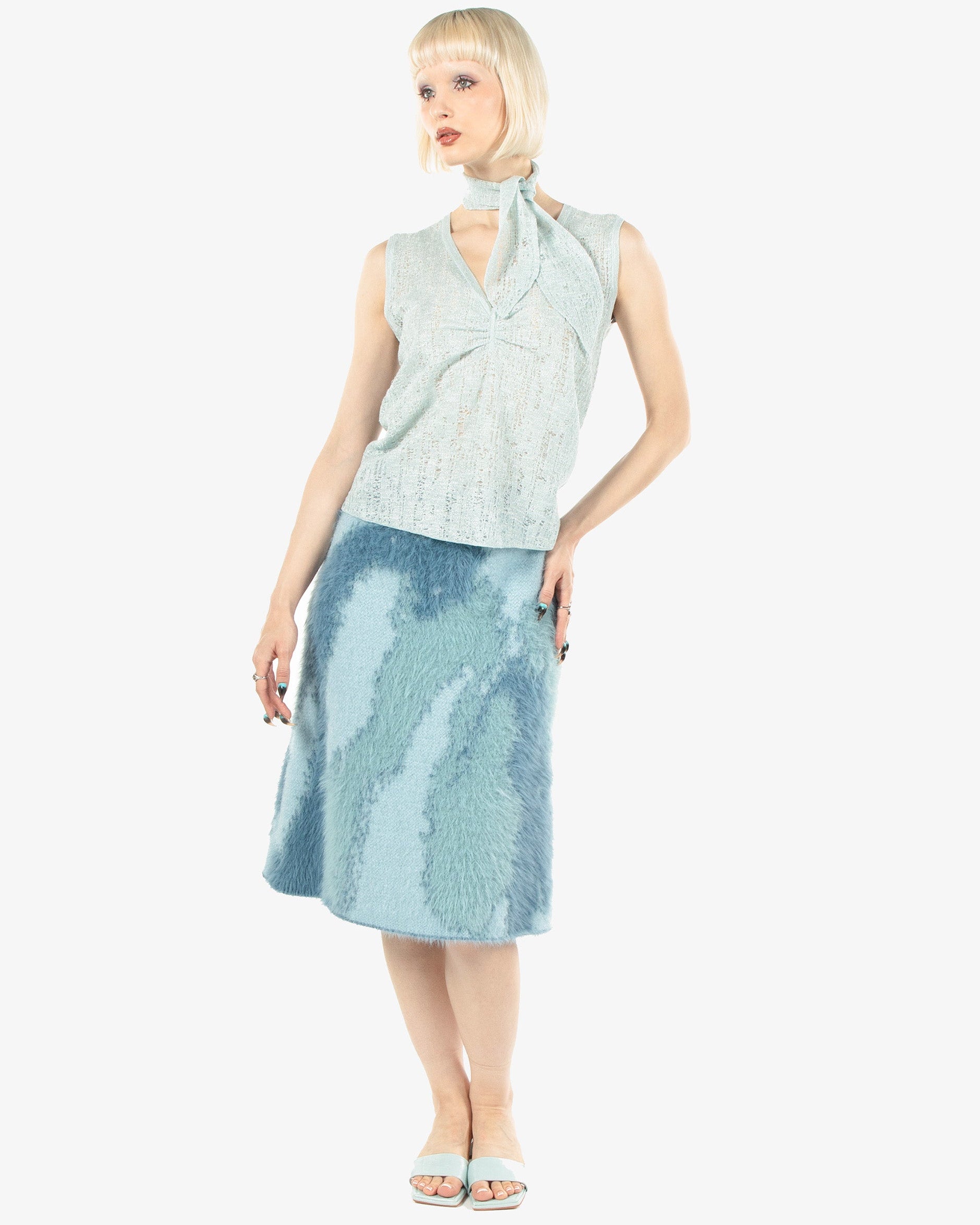 Woman wearing a light blue sleeveless top and skirt on a white background