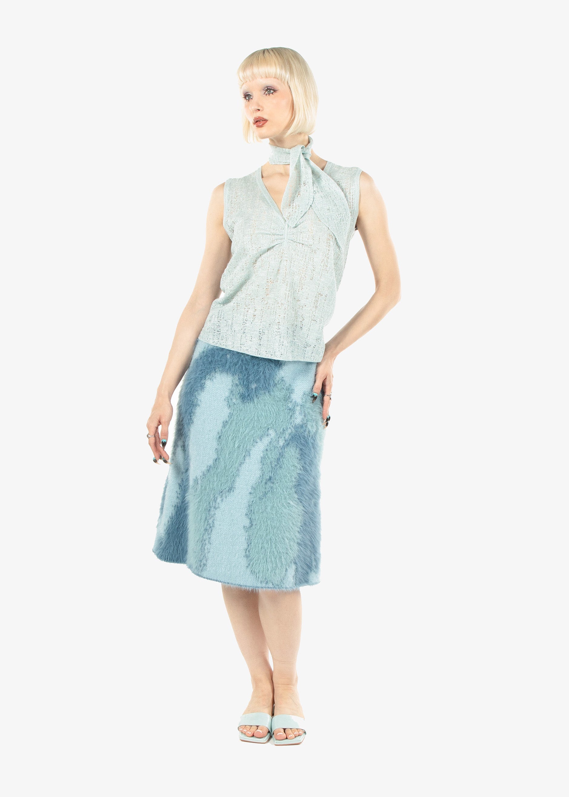 Woman wearing a light blue sleeveless top and skirt on a white background