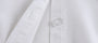 Close-up of a white lab coat with a button on a light gray background