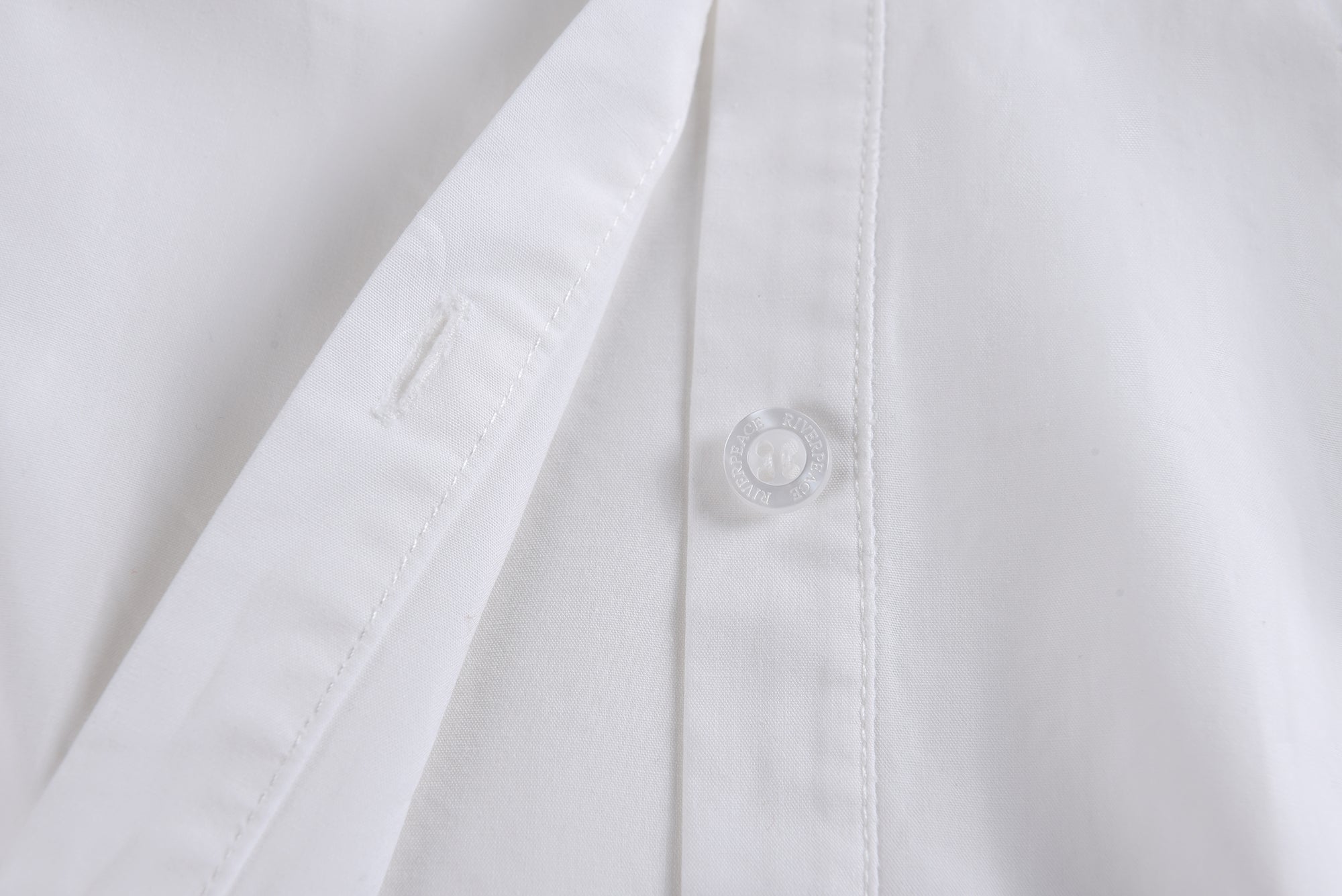 Close-up of a white lab coat with a button on a light gray background