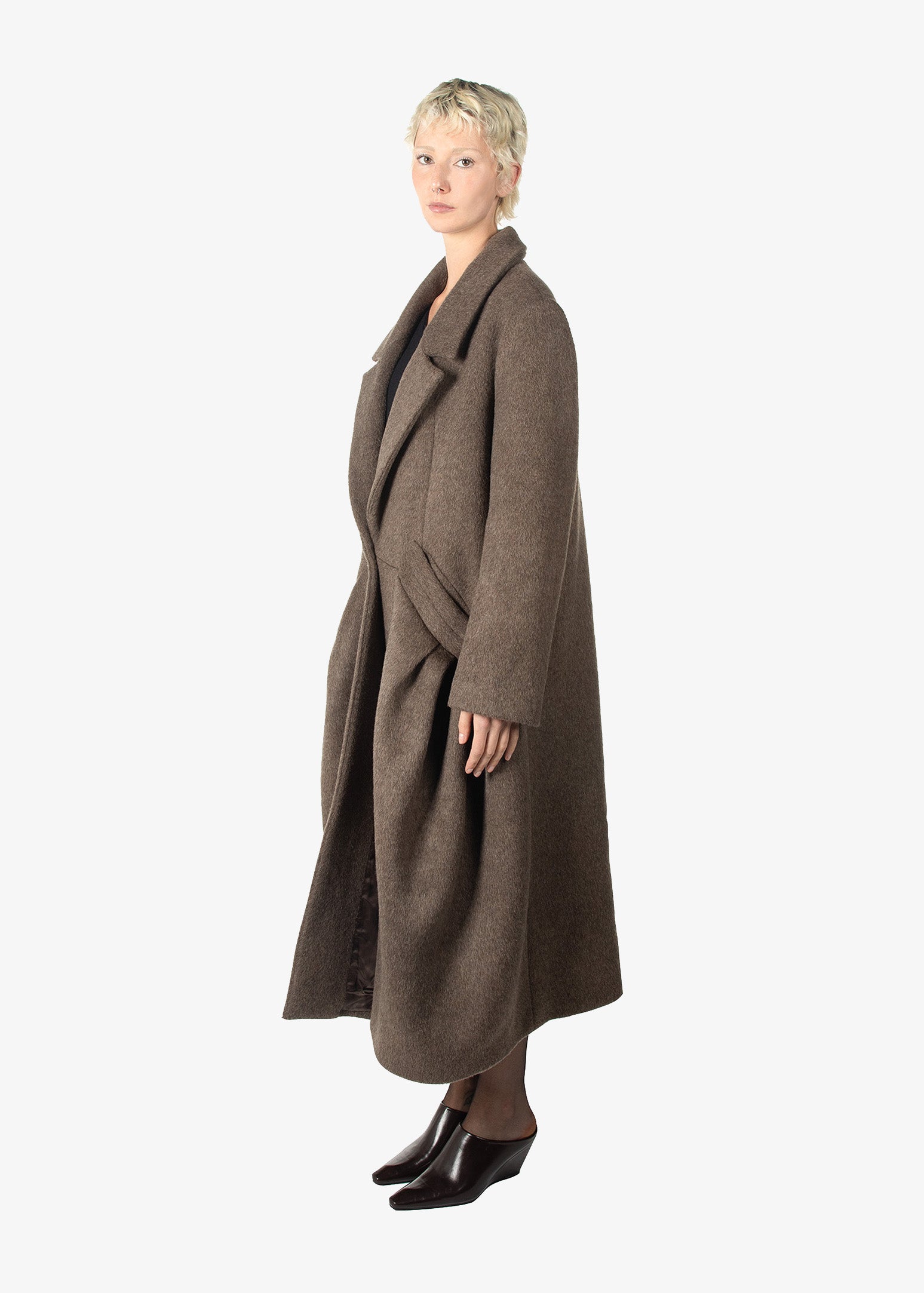 A woman wearing a long brown coat